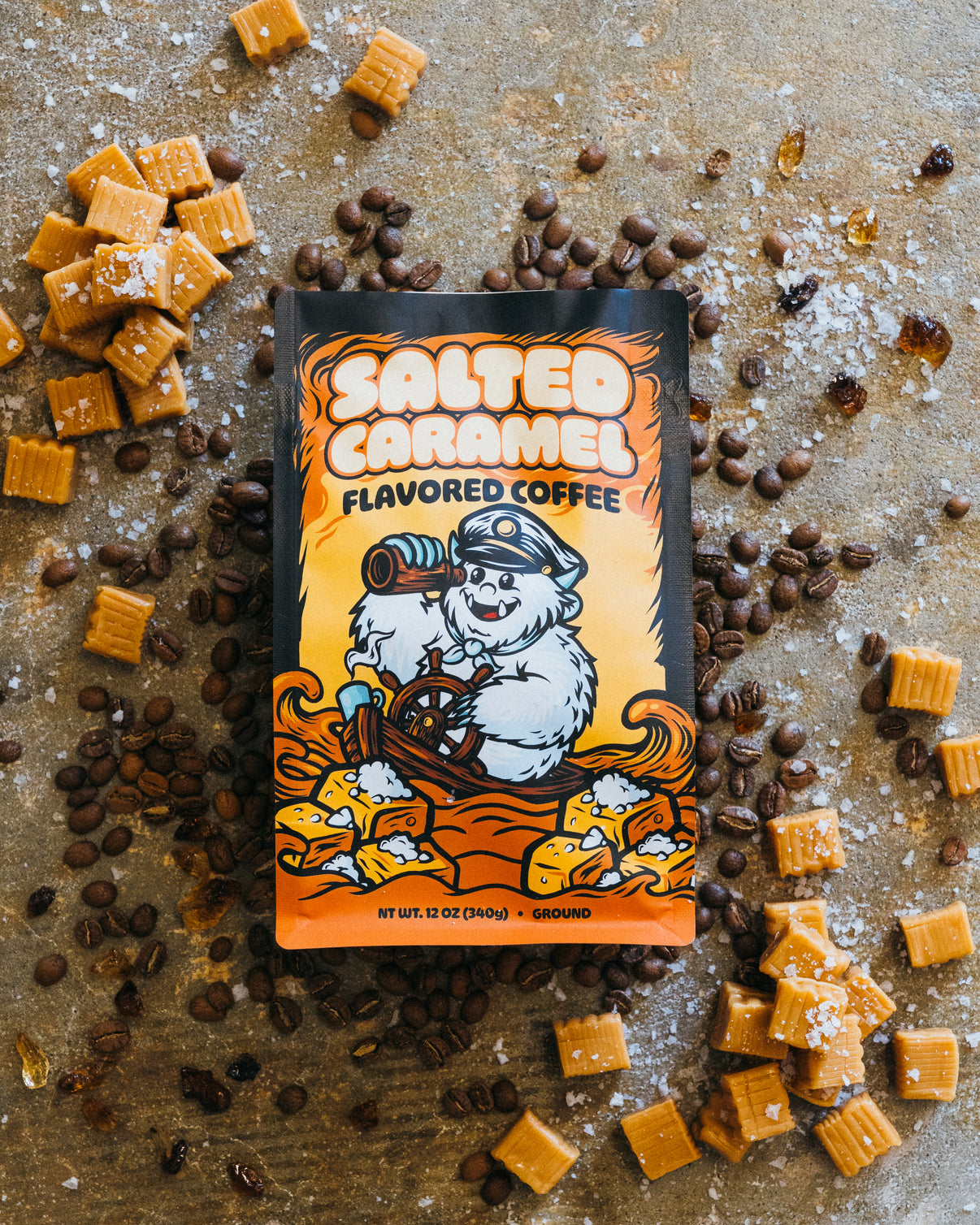 Salted caramel flavored coffee package with caramel pieces and coffee beans on a rustic background